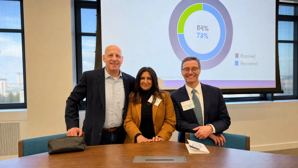 Karl Maersch with two colleagues at a client event, a presentation slide on the screen behind them